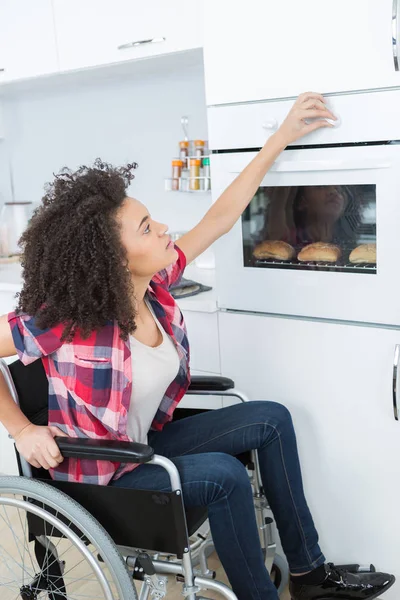Mulher deficiente assar pão no forno de cozinha — Fotografia de Stock