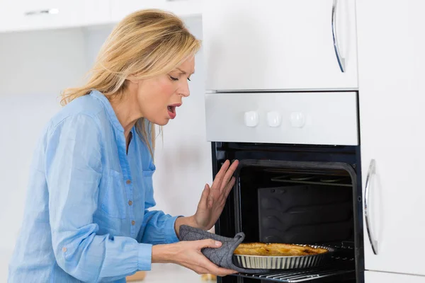 Mujer quemar la mano mientras obtener una tarta fuera del horno — Foto de Stock