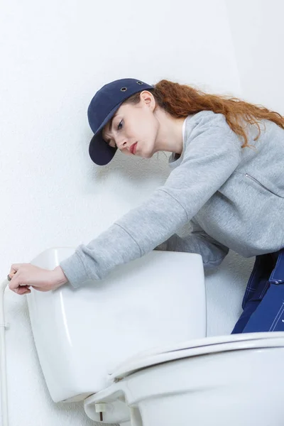 Fontanero femenino reparando cisterna de inodoro en el armario de agua — Foto de Stock