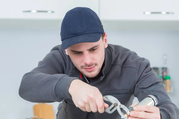 Knappe jonge loodgieter vaststelling van tap op cleints thuis — Stockfoto