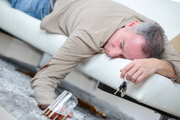 Drunk businessman sleeping with beer on a sofa — Stock Photo, Image