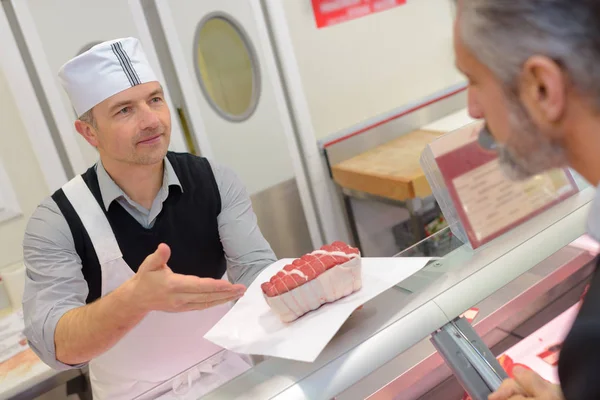 Mannelijke slager seving een mannelijke klant — Stockfoto