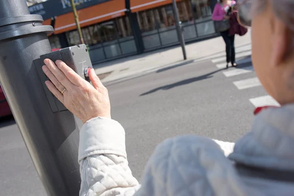 Kvinna vänta för korsning väg med passage-knappen — Stockfoto