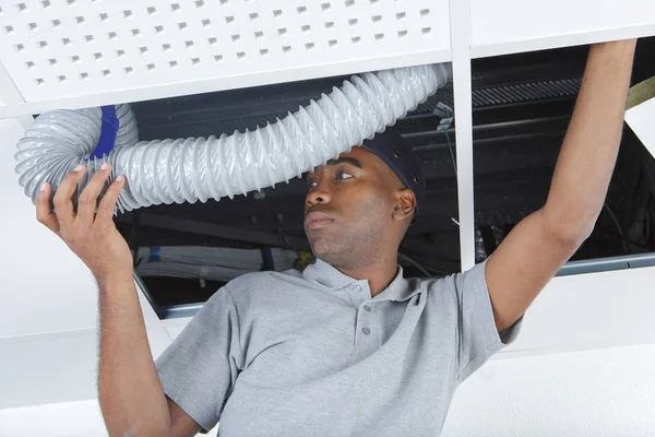 Uomo alimentazione tubo di ventilazione sopra controsoffitto — Foto Stock