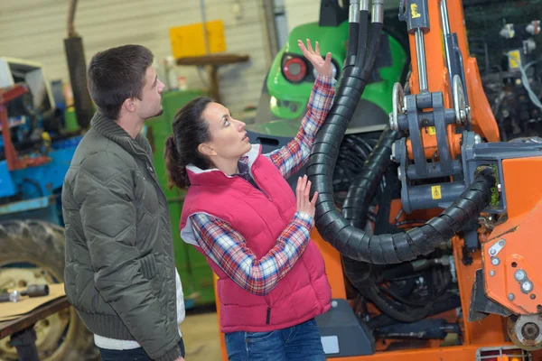 Atraktivní žena prodávat zbrusu nový traktor pro začátečníky farmáře — Stock fotografie