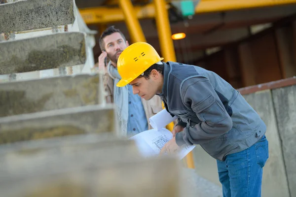 Vista de dos trabajadores que trabajan fuera en una obra de construcción — Foto de Stock