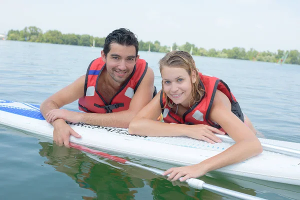 Jovem casal nadando com paddle board em um lago — Fotografia de Stock