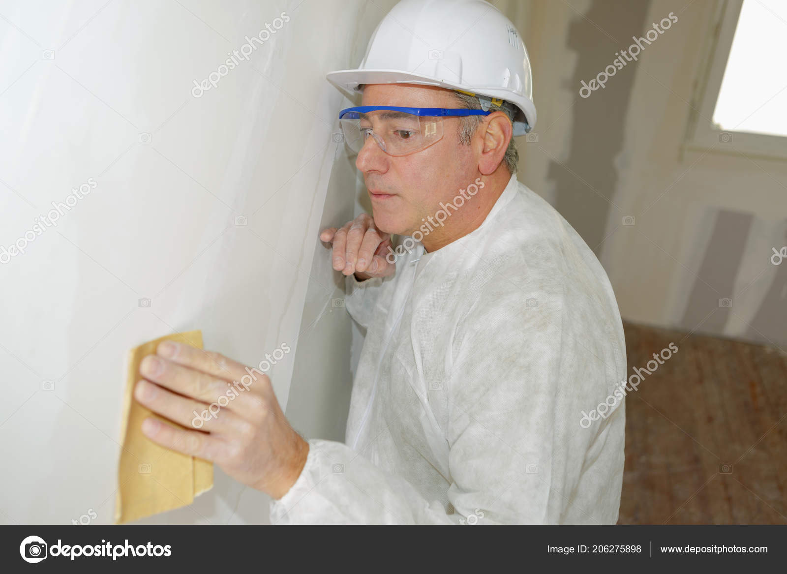 Senior Man Sanding Wall With Sandpaper Stock Photo