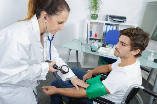 Medico misura la pressione sanguigna di un paziente giovane — Foto Stock