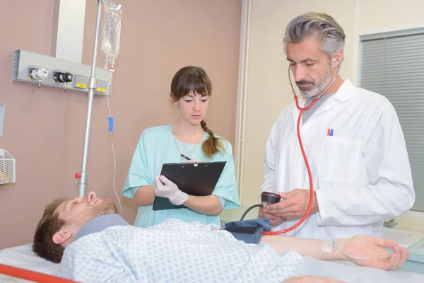 Médico e enfermeiro visitando um paciente em recuperação — Fotografia de Stock