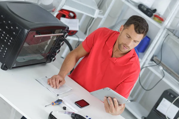 Técnico olhando para tablet enquanto trabalha — Fotografia de Stock