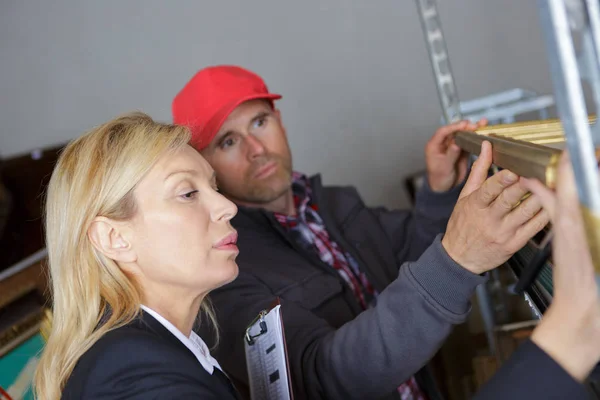 La mujer y el trabajador inspeccionando estantes en el taller —  Fotos de Stock