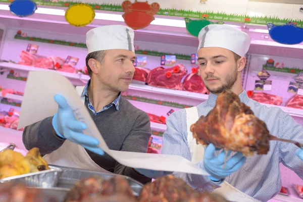 Carnicero enseñando a un joven a vender carne —  Fotos de Stock