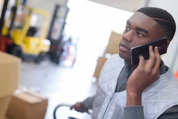 Arbeiter benutzte Handy in Lagerhalle — Stockfoto