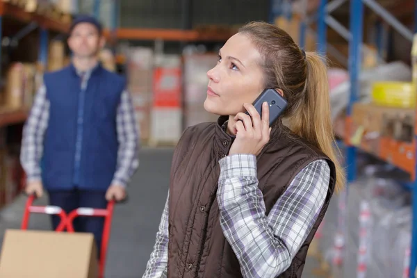 Kvinnlig arbetstagare som använder telefonen i ett lager — Stockfoto