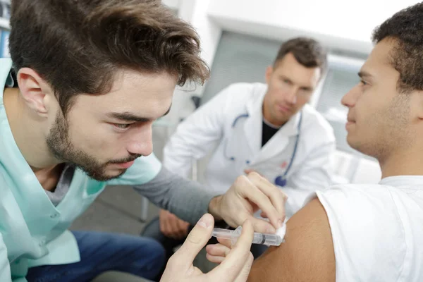 患者に点滴療法を与える若い男性看護師 — ストック写真