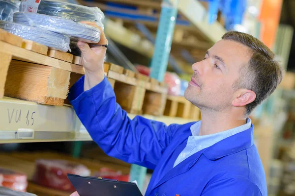 Man taking roll of cable from shelf — Stock Photo, Image