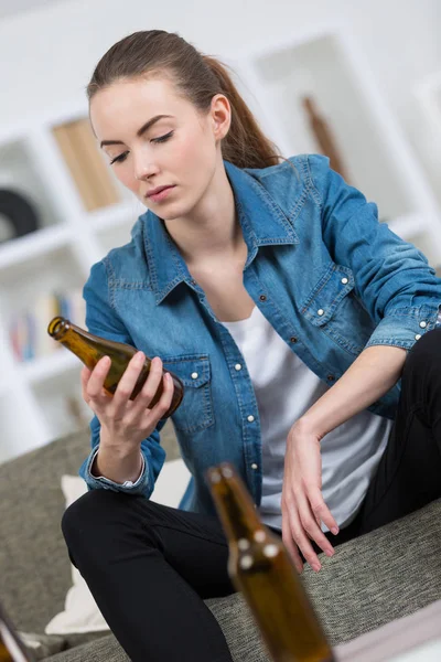 Loira triste e desperdiçada alcoólica mulher sentada em casa sofá — Fotografia de Stock