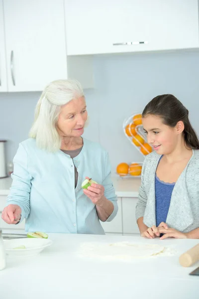 Пожилая леди учит маленькую девочку готовить — стоковое фото