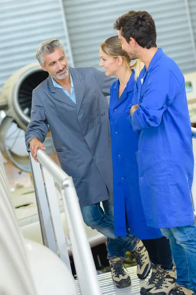 Tres personas de pie en la plataforma junto a los aviones —  Fotos de Stock