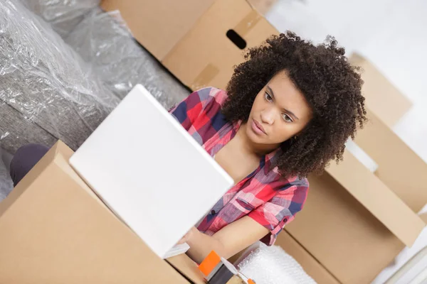 Frau sitzt auf dem Boden neben einer Schachtel mit Laptop — Stockfoto