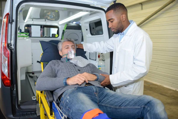 Muž nosí kyslíkovou masku je načten do ambulance — Stock fotografie