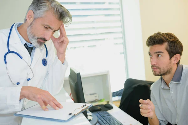 Молодий стресований пацієнт чоловічої статі консультується з лікарем — стокове фото