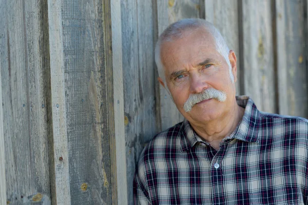 Senior man met witte baard op een houten achtergrond — Stockfoto