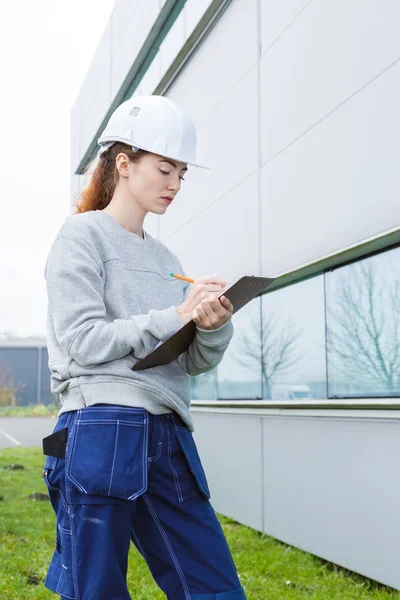 Woman inspecting exterior of building — Stock Photo, Image