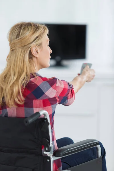 Handicap dame Tv kanaal met afstandsbediening wijzigen — Stockfoto