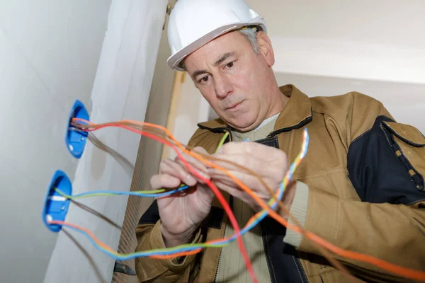 Eletricista instala soquete emparelhado na parede — Fotografia de Stock