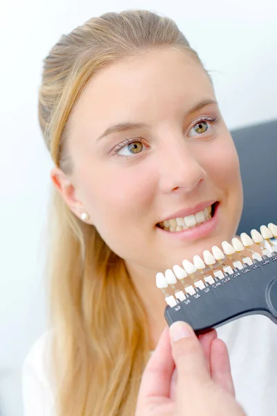 Dentista segurando dentes falsos contra a senhora para combinar a cor — Fotografia de Stock