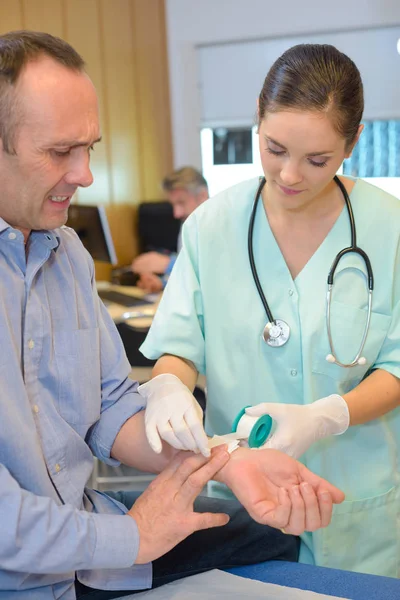 Mann zuckt als Krankenschwester mit Klebeband am Handgelenk — Stockfoto