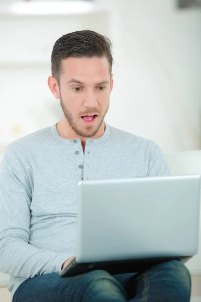 Hombre con portátil haciendo gesto sorpresa — Foto de Stock