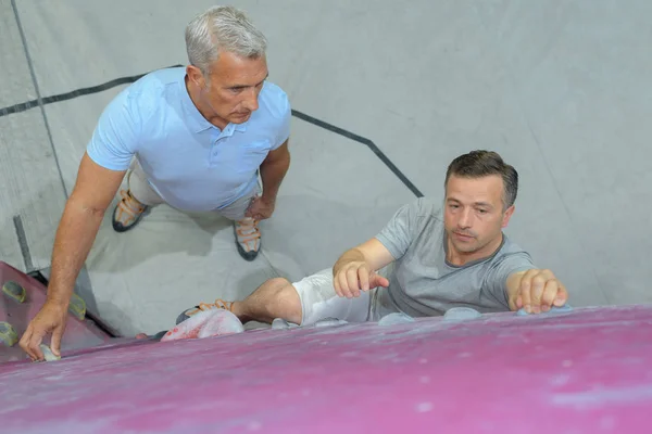 Hombre aprendiendo a escalar en el muro de escalada —  Fotos de Stock