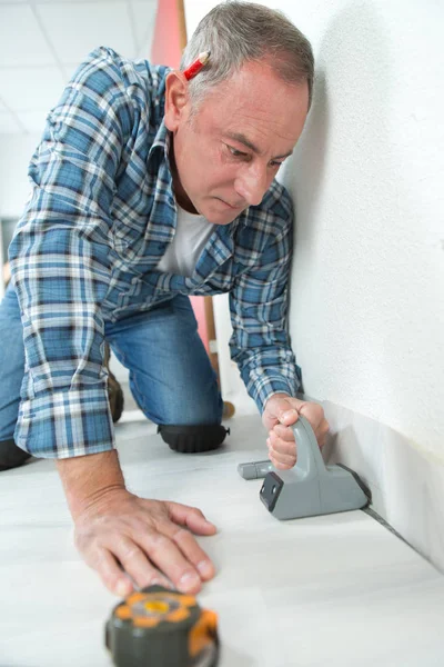 Homem instalando piso laminado leve em uma sala — Fotografia de Stock