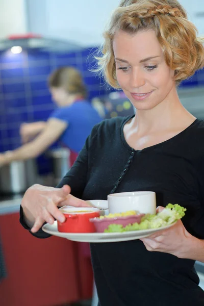 Lächelnde Kellnerin nimmt Teller in Restaurantküche — Stockfoto