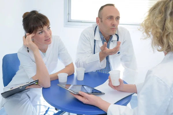 Médecins et infirmier relaxant assis au bureau — Photo