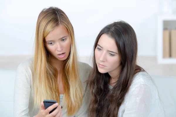 Dos mujeres jóvenes disgustadas mirando el teléfono móvil — Foto de Stock