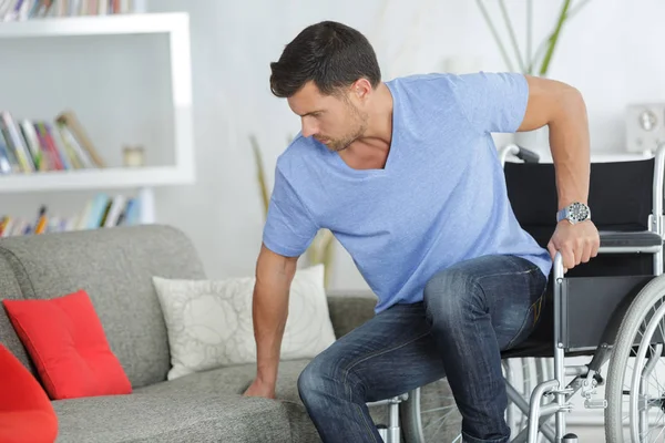 Disabile uomo cercando di sedersi su un divano — Foto Stock