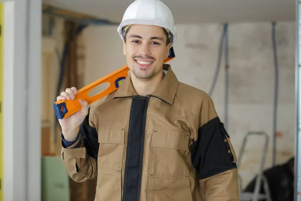 Construtor profissional posando com nível de espírito no local de construção — Fotografia de Stock