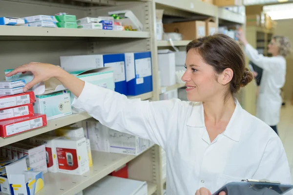 Sonriente atractiva joven farmacéutica en la farmacia — Foto de Stock