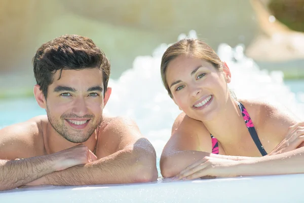 Porträt eines Paares, das über die Seite des Schwimmbades blickt — Stockfoto