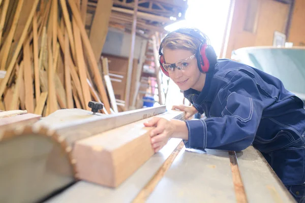 Vrouwelijke timmerman met behulp van tabel zag hout in werkplaats — Stockfoto