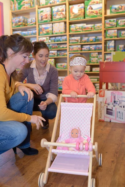 Matka i córka z atrakcyjnym sprzedawca w sklepie z zabawkami — Zdjęcie stockowe