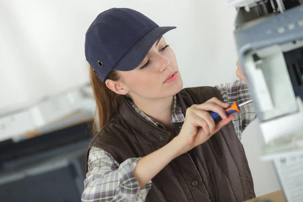 Female technician using a screwdriver for fixing printer — Stock Photo, Image