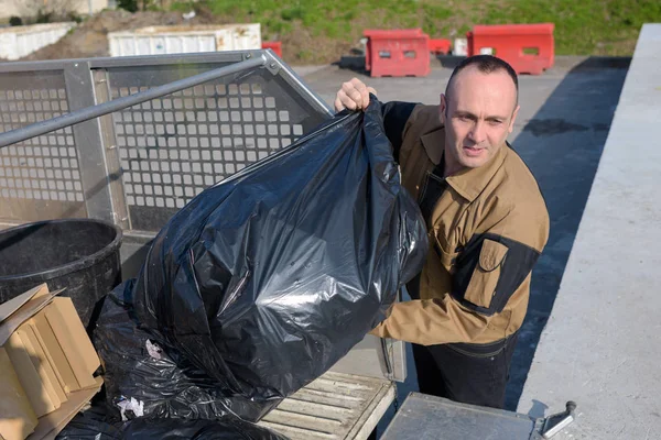 Trabalhador derrubando sacos de lixo — Fotografia de Stock