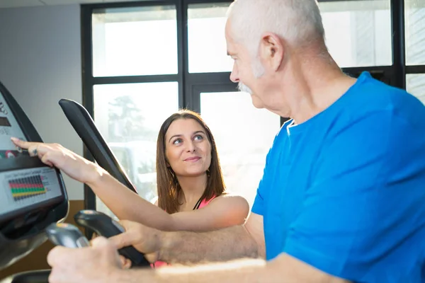 Hombre mayor caminando con entrenador en gimnasio — Foto de Stock