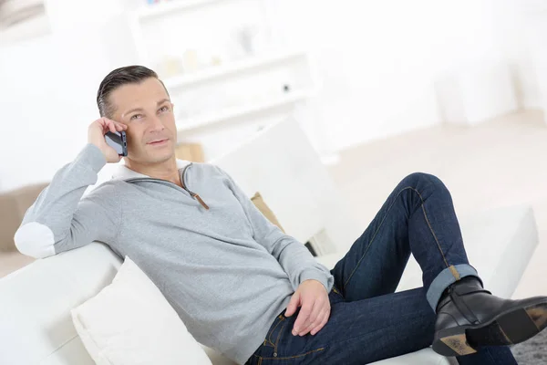 Schöner Mann am Telefon sitzt auf einem Sofa — Stockfoto