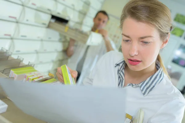 Apotekspersonal tittar på läkemedelsförpackningen i apotek — Stockfoto